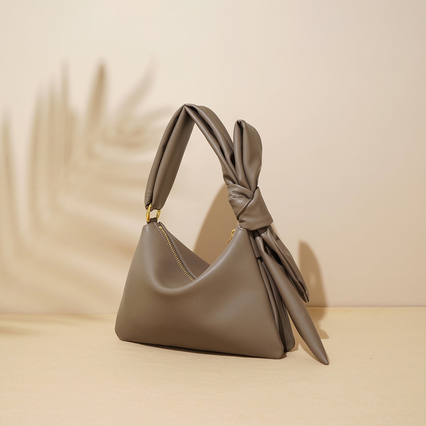 Gray handbag with a knot detail on a beige background