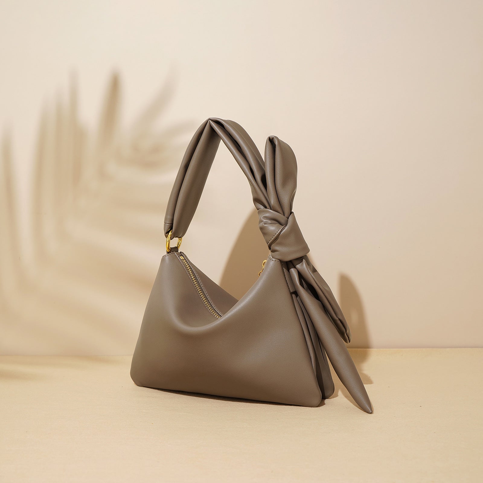 Gray handbag with a knot detail on a beige background